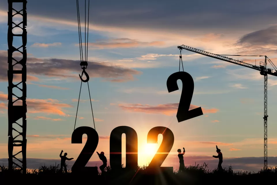 A silhouette of construction workers lowering larger numerals into place to form 2022.